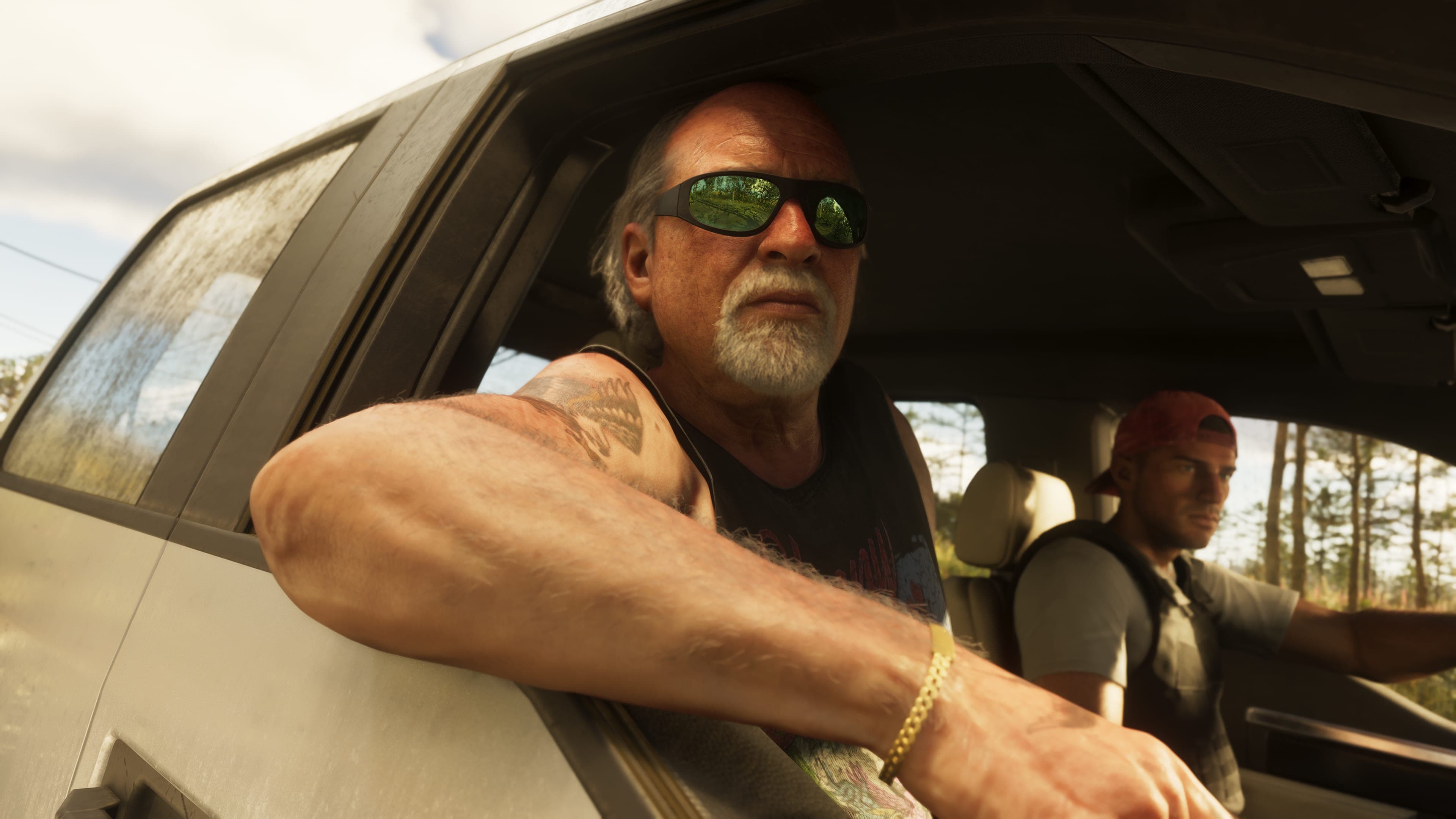 Brian Heder in sunglasses with his arm out of a car window, another man in the passenger seat