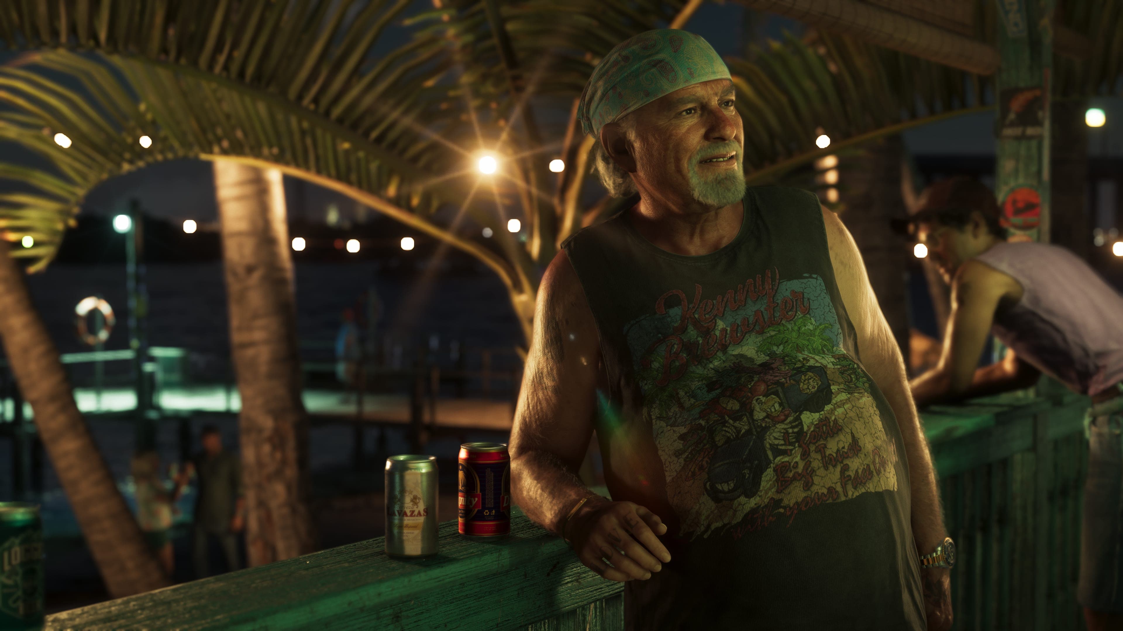 Brian Heder standing at a strung-light beach bar in a cut-off shirt