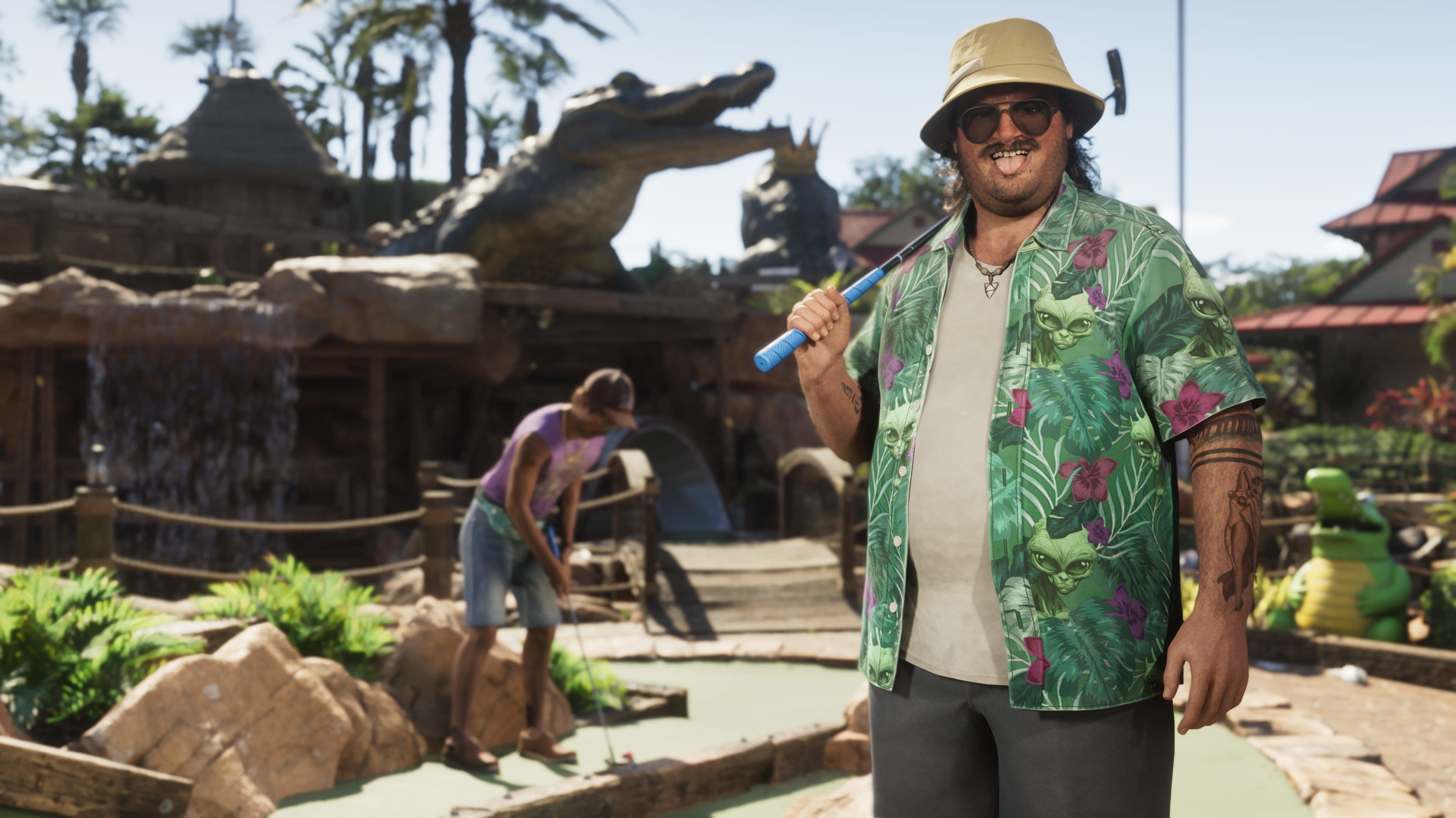 Cal Hampton in a bucket hat and floral shirt beside a gator enclosure