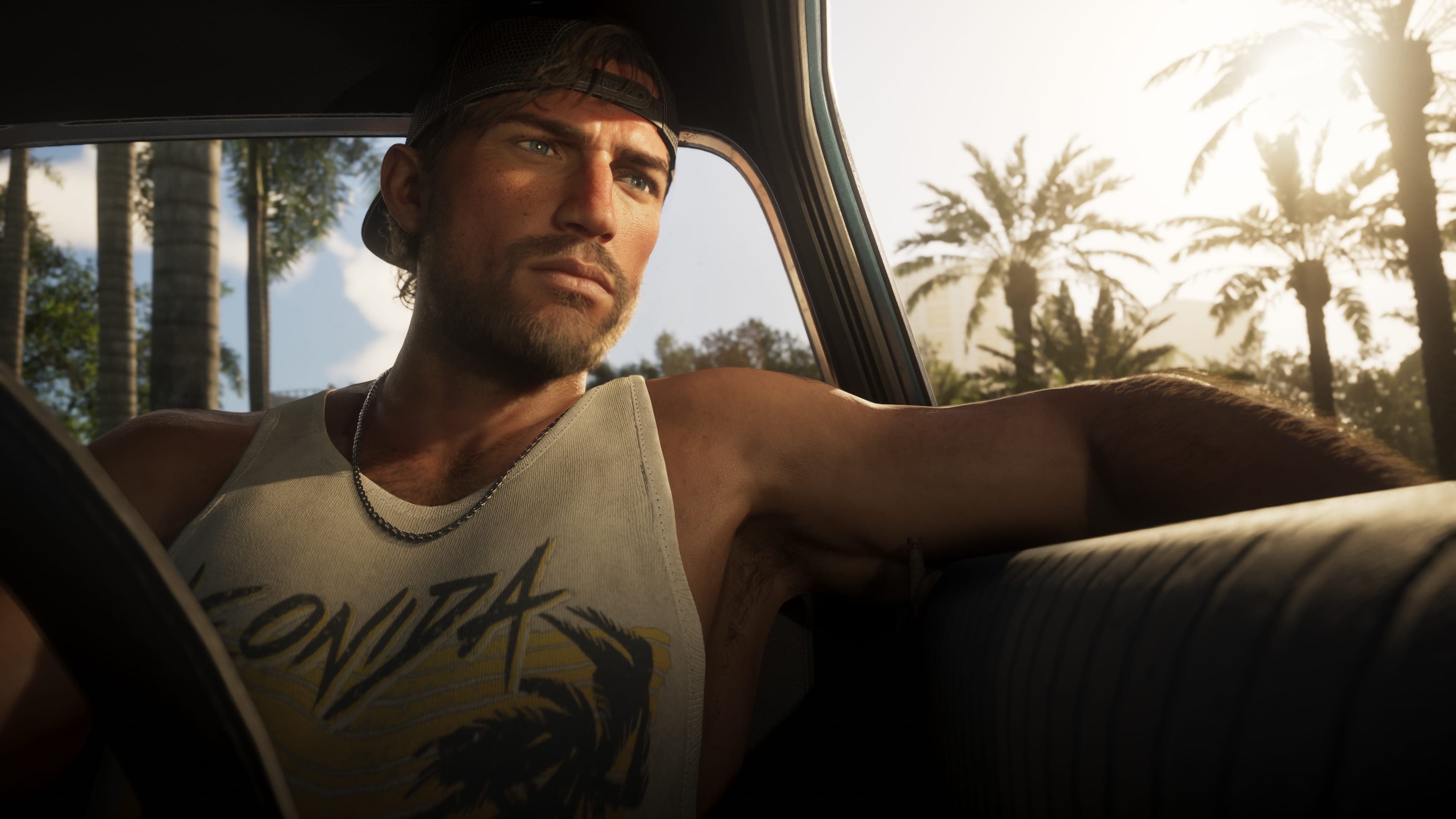 Jason Duval slouched in a car seat in a vest and cap, palms visible through the window