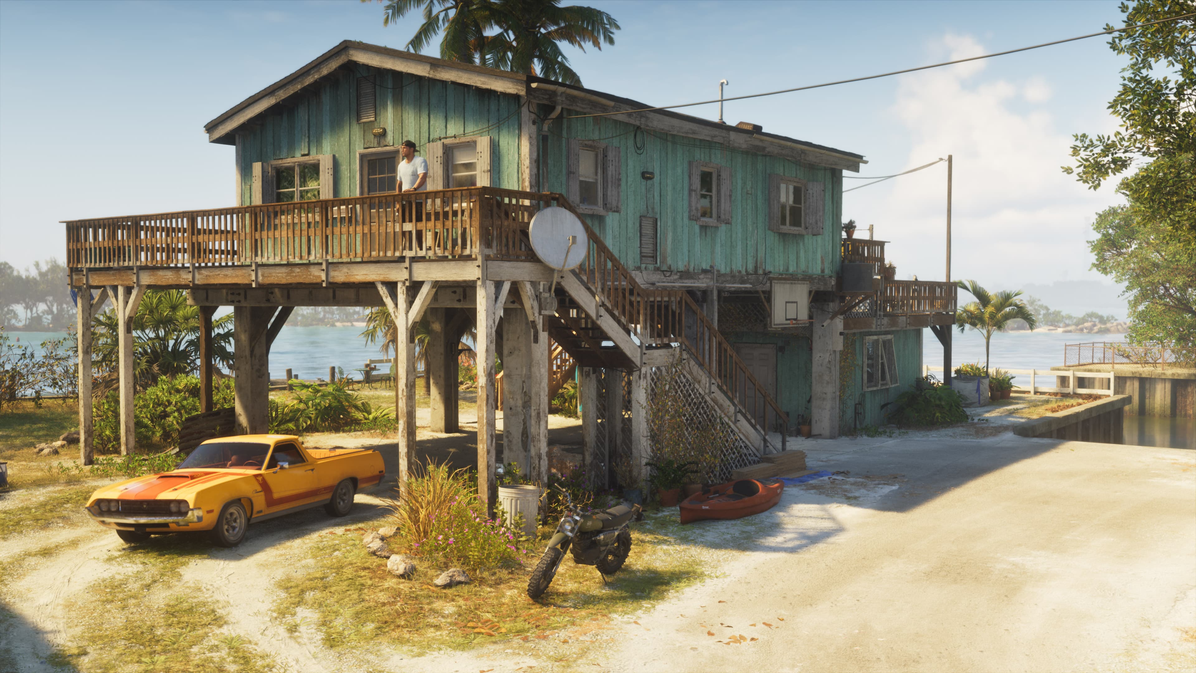 An orange muscle car parked beneath a blue stilt house on the waterfront