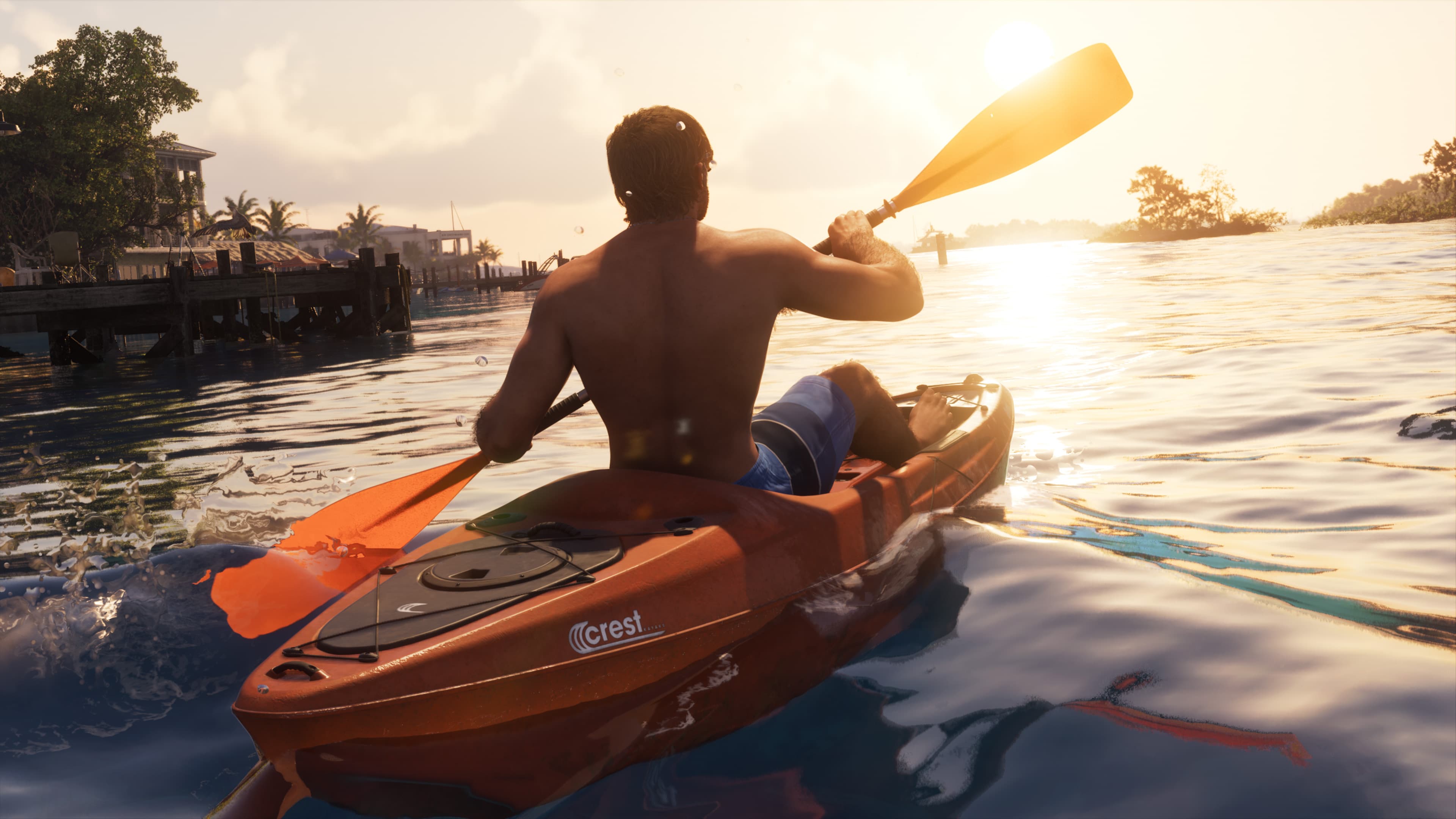 A man paddling an orange kayak across calm water at sunrise