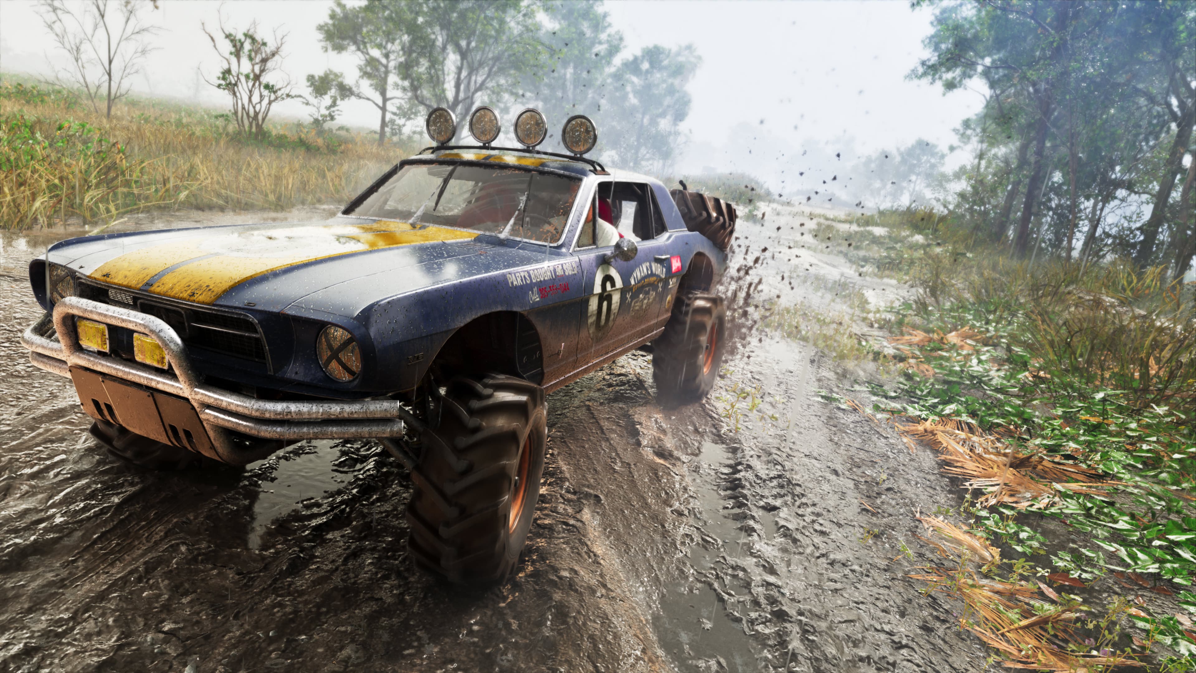 A yellow and black off-road buggy throwing up spray on a flooded dirt track