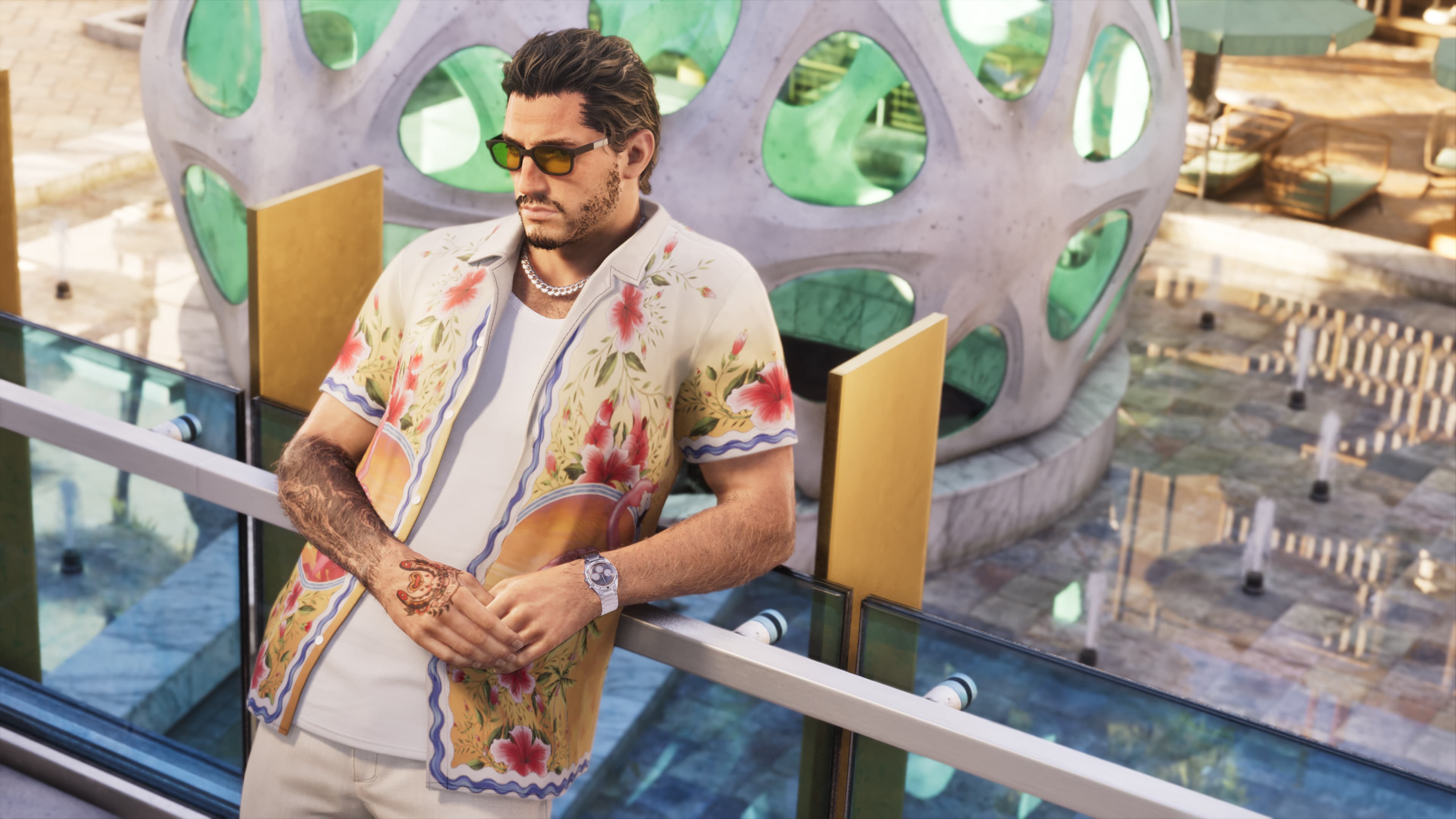 A man in a patterned shirt and sunglasses leaning on a railing