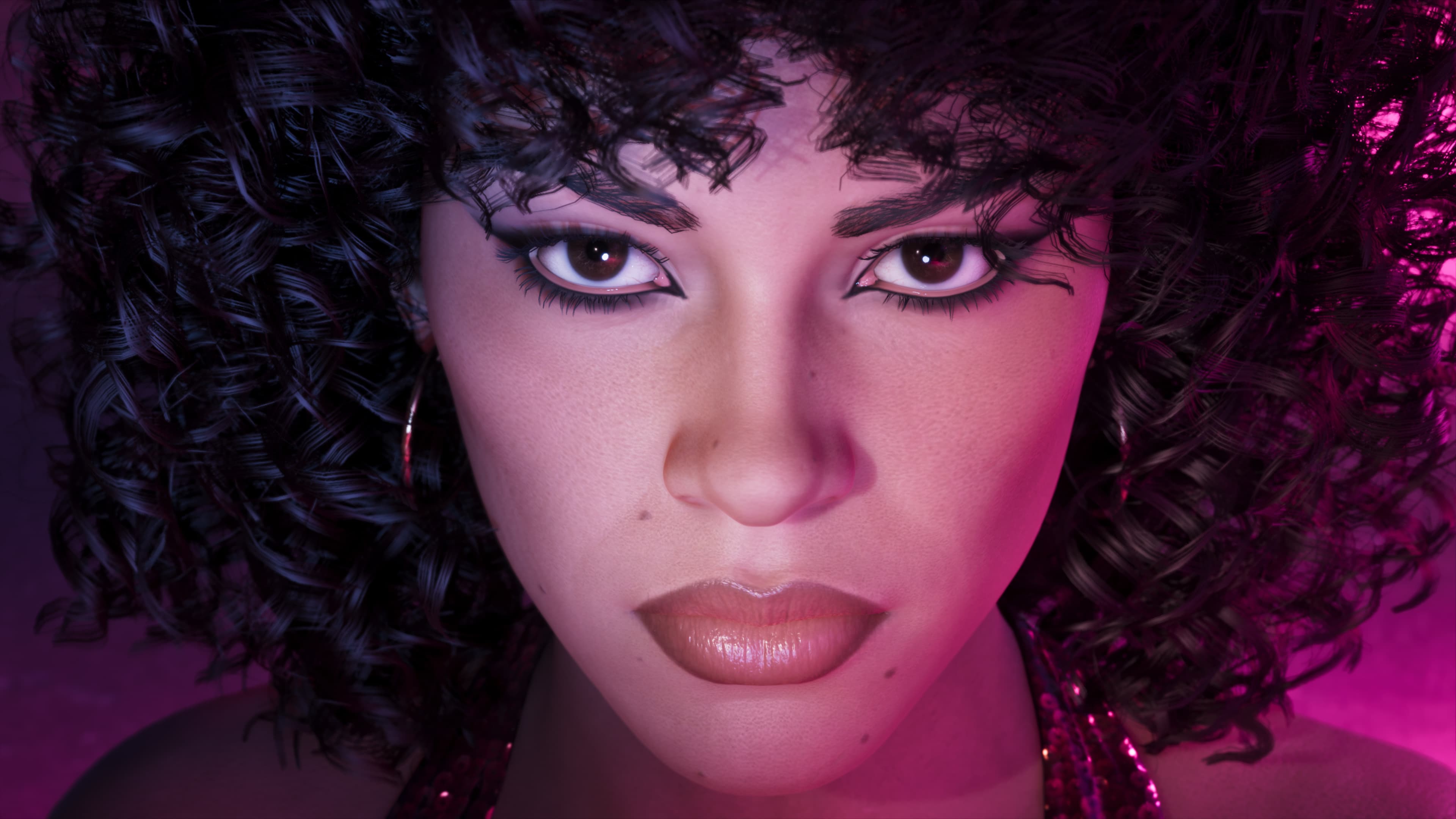 Close portrait of a woman with a large curled afro under pink lighting